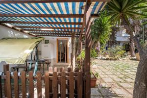 una pérgola de madera con una valla delante de una casa en Appartamento Depandance 2 Villa Ada Punta Prosciutto, en Punta Prosciutto