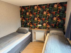 two beds in a room with a floral wallpaper at Voorts Broekhuisje 5 in Voorthuizen +20 photos