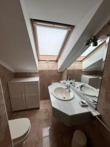 a bathroom with a sink and a toilet and a skylight at Gestiona2R- Casa grande para 12 en Llanes 6 dormitorios Jardín y espacio exterior in Llanes +38 photos