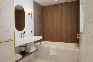 a bathroom with a tub and a sink and a mirror at Les Sables Blancs in Concarneau