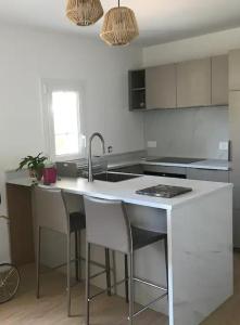 a kitchen with a sink and a counter with stools at charming place ideally located in Ciboure