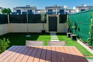 a backyard with a fence and a lawn with chairs at The Garden House in Alicante