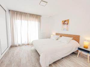 a white bedroom with a large bed and a window at The Garden House in Alicante