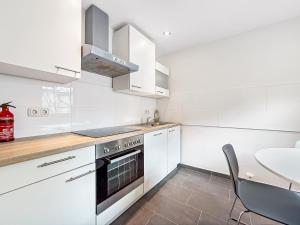 a kitchen with white cabinets and a stove and a table at Heart of Hannover Apartment in Hannover