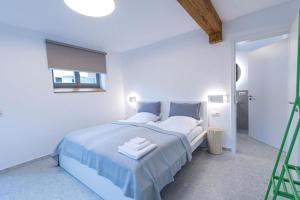 a white bedroom with a large bed with blue sheets at Landurlaub mit neugierigen Blicken in den Pferdestall, eingezäuntem Garten, Kamin und Sauna in Rot am See