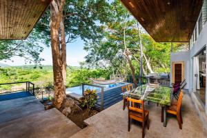 VillarrealにあるHammock House Your Private Oasis Near Tamarindoの木のあるパティオ(テーブル、椅子付)
