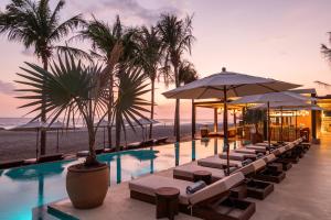 ein Pool mit Liegestühlen und Sonnenschirmen direkt am Strand in der Unterkunft Casa Yati in Santa María Tonameca