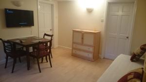 Habitación con mesa, sillas y TV. en Mayville House Flat en Cheltenham
