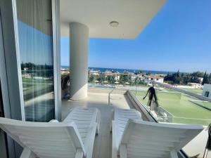 a balcony with white chairs and a tennis court at Sea Breeze Suite by the Sea in Vokolidha