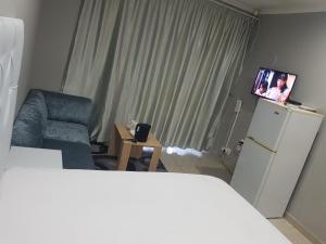 a room with a refrigerator and a chair and a tv at Reitz Guest House in Mahikeng