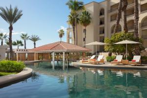une piscine avec des palmiers en face d'un hôtel dans l'établissement Dreams Los Cabos Suites Golf Resort & Spa, à Cabo San Lucas