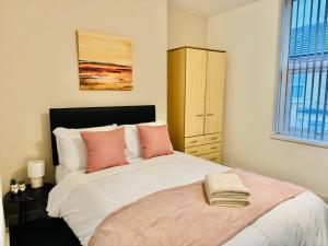 a bedroom with a large bed with pink pillows at Quarto 4 casa compartilhada no L7 in Liverpool