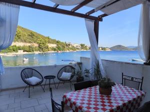 a patio with a table and chairs and a view of the water at Apartman Olly in Klek