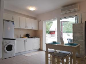 a kitchen with a washer and dryer and a table at Apartman Olly in Klek