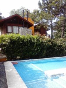 a swimming pool in front of a house at Cabañas Entreverdes in Villa Gesell