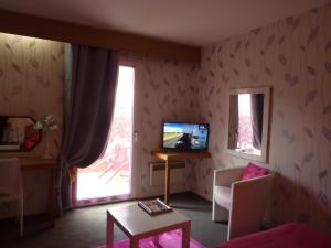 - un salon avec une télévision, un canapé et une table dans l'établissement Hôtel A La Renommée, à Saint-Père