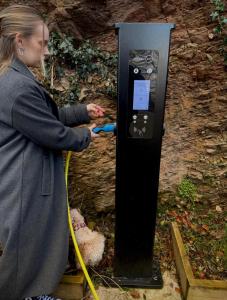 a woman is using a pay phone at a parking meter at Clifftop Watch, River View and Balcony, 1 BR, Parking, Beach 10 min walk in Lynmouth +14 photos