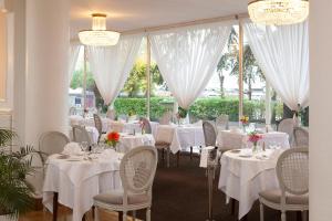 a dining room with white tables and chairs and white curtains at Logis Hotel Royal Saint-Mart in Royat