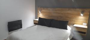 een slaapkamer met een wit bed met een houten hoofdeinde bij cabañas sunrise in Merlo
