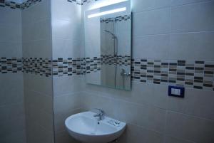 Baño blanco con lavabo y espejo en Appartamenti Corneliani, en Sirmione