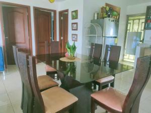 een eetkamer met een glazen tafel en stoelen bij Habitación confort in Puyo +14 foto's