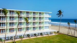 an exterior view of a hotel with palm trees and the beach at Pierre Mundo Imperial Riviera Diamante Acapulco All Inclusive in Acapulco