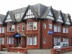 a large red brick building with a car parked in front at Collingwood Hotel in Blackpool