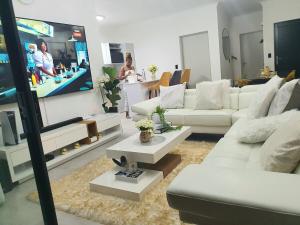 a living room with white couches and a flat screen tv at HMT Modern House in Centurion