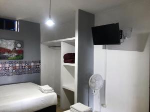a small bedroom with a bed and a tv on the wall at Hotel Gandag in Orizaba