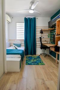 a bedroom with a bed and a desk with a blue curtain at Appartement design & confort- Route des hôtels in Le Gosier