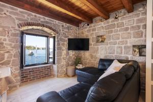 Apartman Sun 1 في شيبينيك: غرفة معيشة مع أريكة وجدار حجري