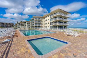 a resort with a pool and chairs and a building at Beachfront 4th Floor Condo with Spectacular Beach & Ocean Views and Pool! in Bottle Island