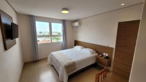 a bedroom with a bed and a large window at EKT Executive Hotel in Pelotas