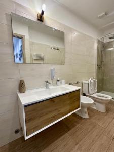 łazienka z umywalką, toaletą i lustrem w obiekcie Revel Apartments Central Station To Cinque Terre w mieście La Spezia