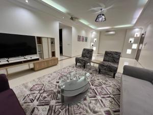 a living room with a flat screen tv and chairs at بيت نوف للضيافة in Buraydah