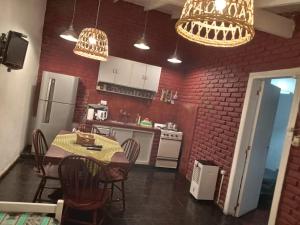 a kitchen with a table and chairs and a red brick wall at La Casita de Mogotes in Mar del Plata