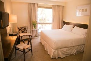 a hotel room with a bed and a desk and a window at Hotel Costa Real in La Serena