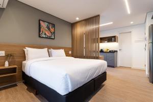 a bedroom with a large bed and a kitchen at Pivô Pamplona by Viva - Apartamentos novos e espaçosos ao lado da Av Paulista in Sao Paulo