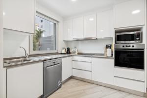 een witte keuken met witte kasten en apparaten bij Indigo Apartment By The Madeira Luxury Collection in Funchal