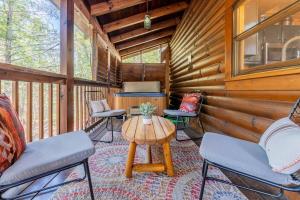 eine Veranda mit Stühlen und einem Tisch in einer Hütte in der Unterkunft Cozy Spacious Cabin with Hot Tub, BBQ near Parkway in Pigeon Forge