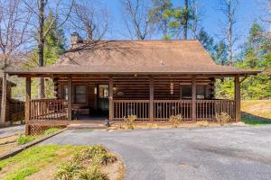 eine Blockhütte mit einer Veranda und einer Einfahrt in der Unterkunft Cozy Spacious Cabin with Hot Tub, BBQ near Parkway in Pigeon Forge
