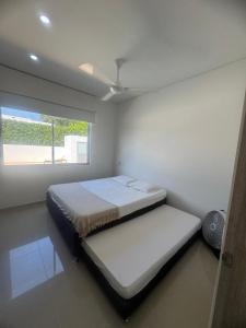 a white room with a bed with a window at Beautiful house,Carmen de Apicalá in San Antonio