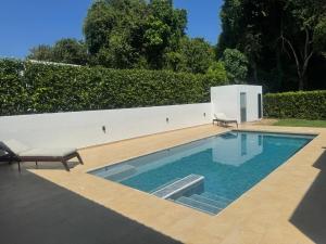 a swimming pool with two chairs next to a white wall at Beautiful house,Carmen de Apicalá in San Antonio +4 photos