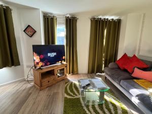 a living room with a couch and a flat screen tv at Town centre 1 Cozy king size bed ensuit shower in Huntingdon