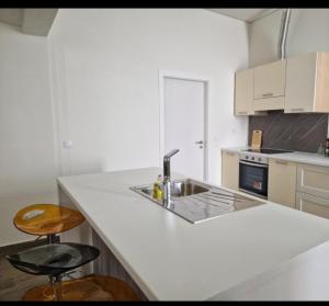 a white kitchen with a sink and two bar stools at Casa do Leão in Évora +5 photos