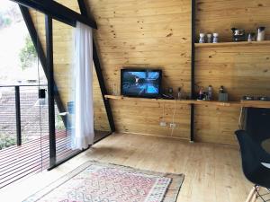 a living room with a tv in a wooden wall at Chalé Mon Amour, puro design no ar puro in Campos do Jordão +45 photos