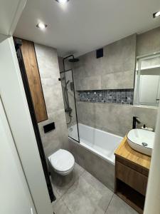 a bathroom with a toilet and a tub and a sink at Marszałkowska City Center Apartment With Working Space in Rzeszów +9 photos
