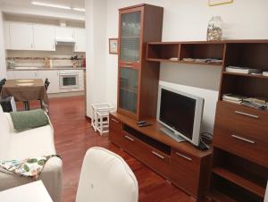 a living room with a tv on a wooden entertainment center at Apartamento Rio Grande in Fisterra