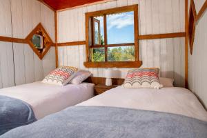 two beds in a room with a window at La Casa de Alerce in Chacao