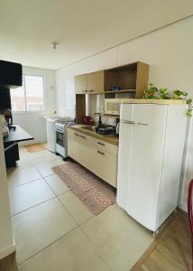 a kitchen with white appliances and a white refrigerator at Ap de 2 quartos com AR, wifi e garagem - Bairro tranquilo in Santo Ângelo